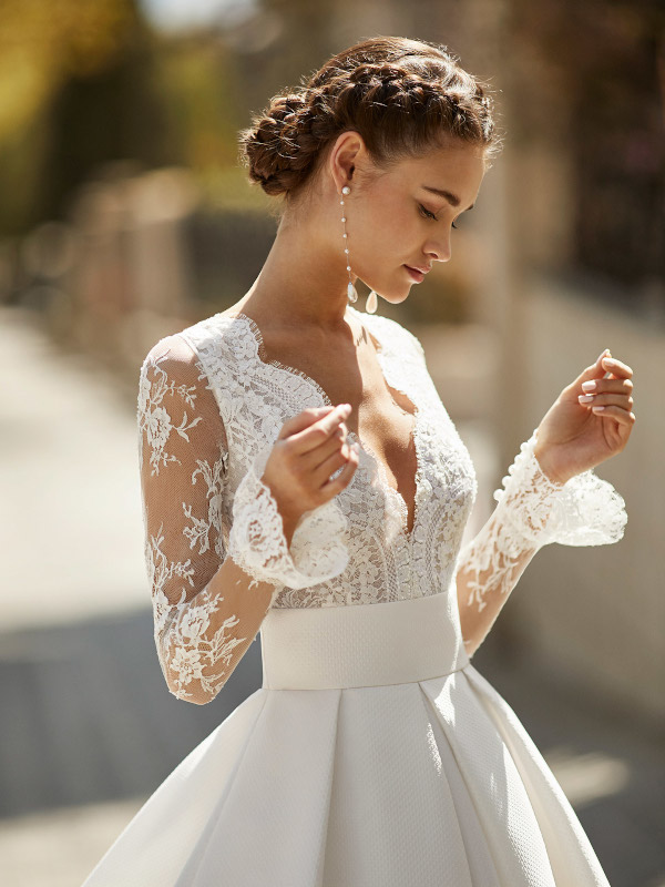 Vestido de novia alta costura con escote pico manga larga con tul y encaje, falda gran volumen y pliegues en la cintura.