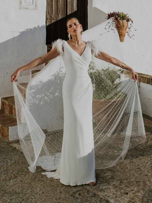 Vestido de novia alta costura con cuerpo drapeado, escote en V y plumas en el hombro y espectacular capa..
